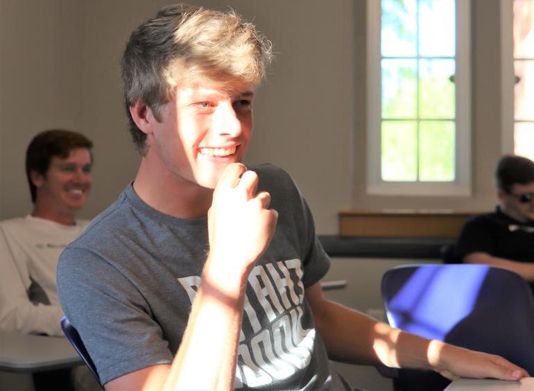 一名身穿灰色t恤的大学生在UTC的销售课上大笑. 罗林斯商学院.
